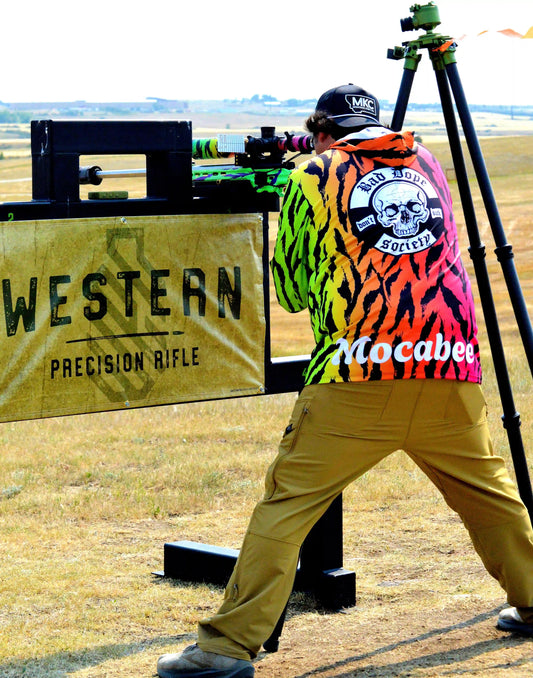 Precision rifle shooter engaging targets off a barricade at a Western Precision Rifle match, wearing a Bad Dope Society sun shirt.